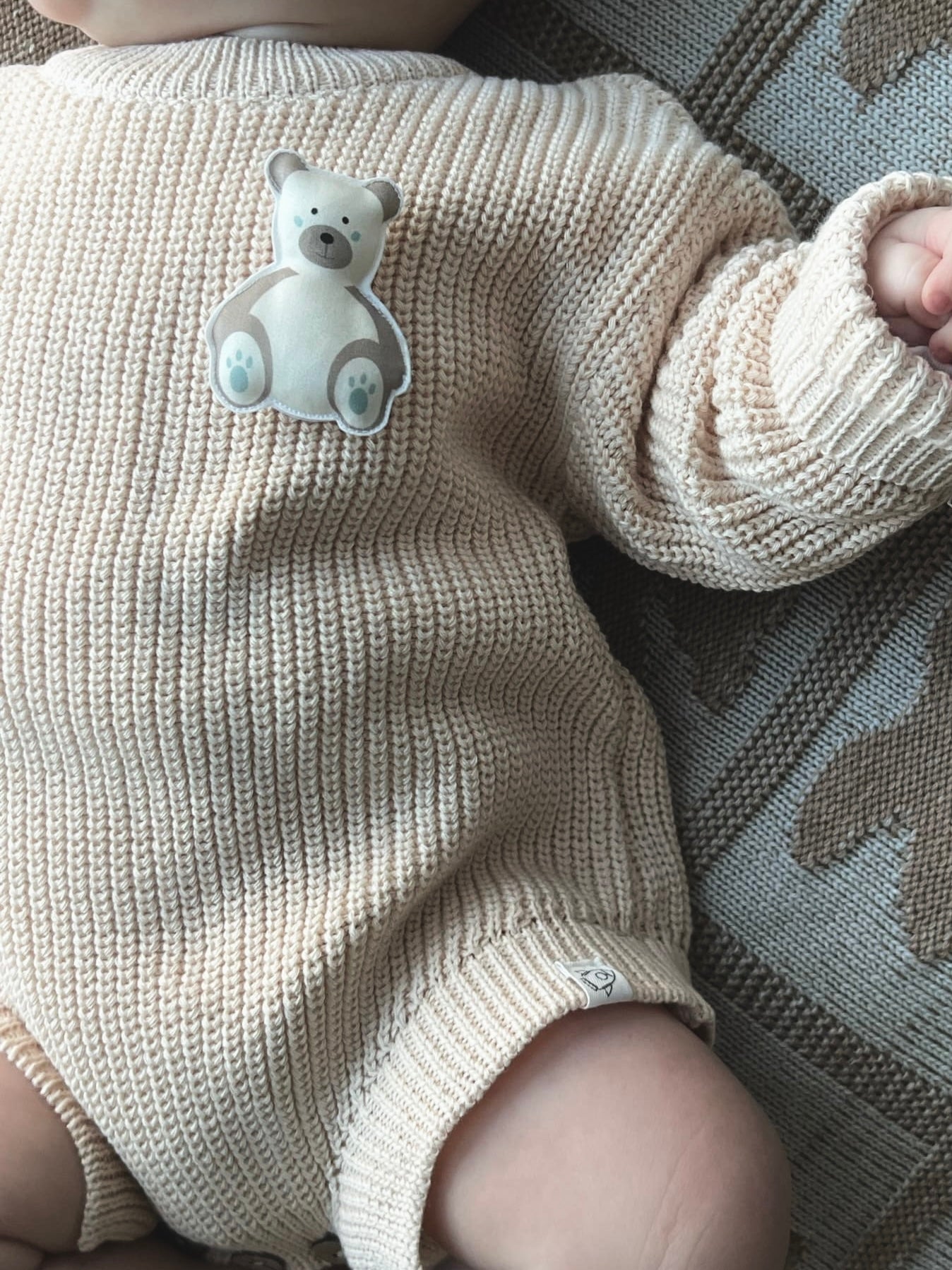 Beige knitted baby romper and 2 changeable decorations